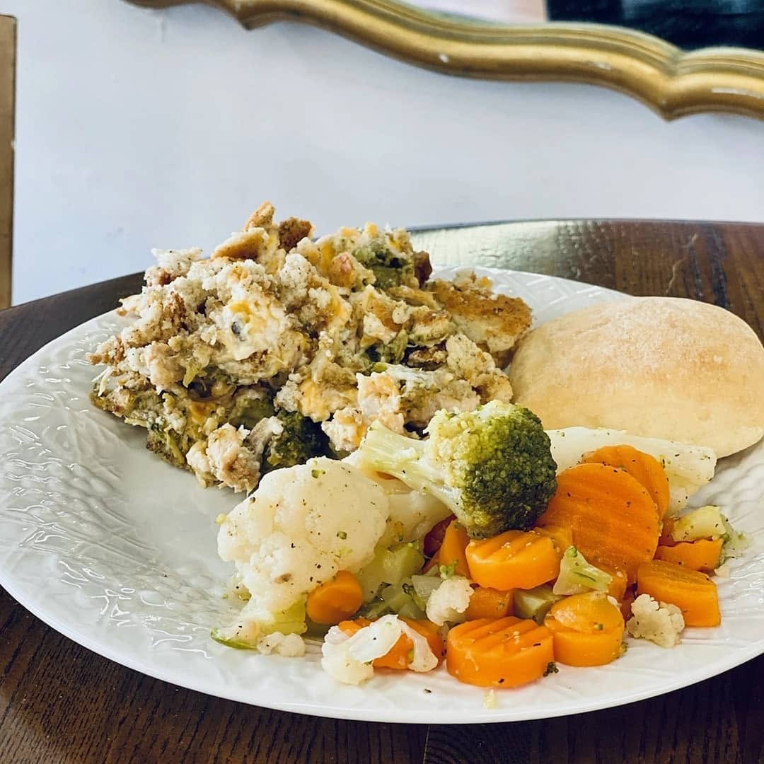 Plated chicken casserole with seasoned vegetables and a roll