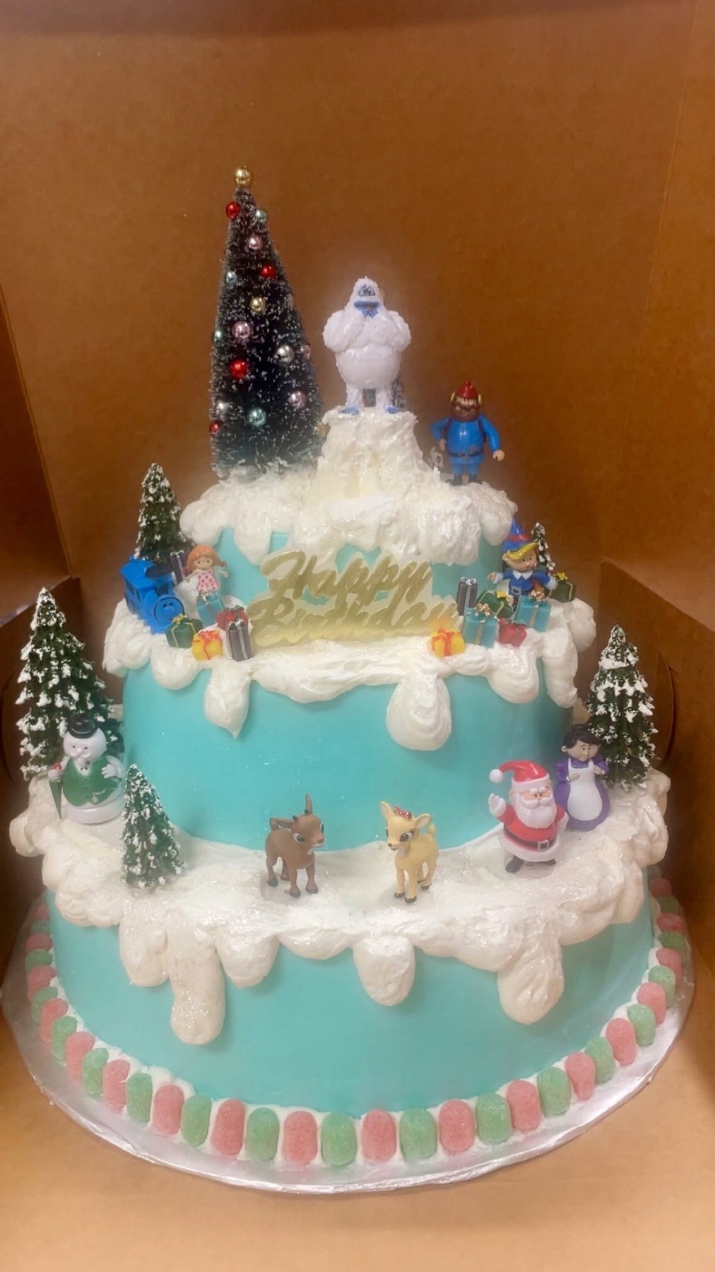 Tiered Christmas cake decorated with winter characters and snowy details